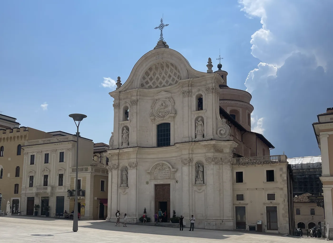 Barokke kerk aan een leeg plein in een Europese stad onder felle zon en strakblauwe lucht