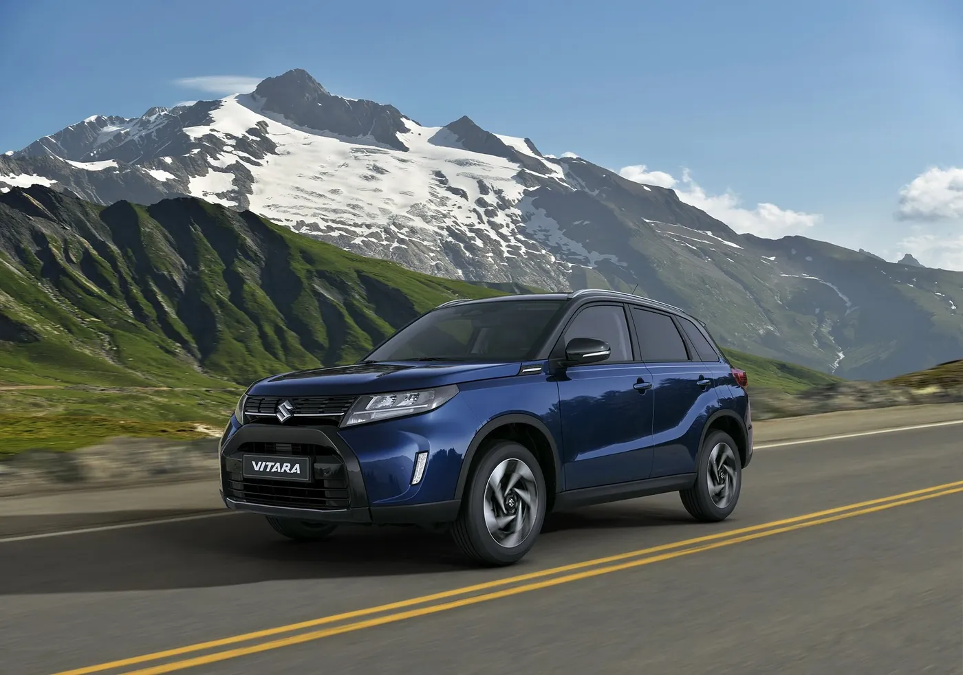 Blauwe Suzuki eVitara, volledig elektrische SUV, rijdend op bergweg