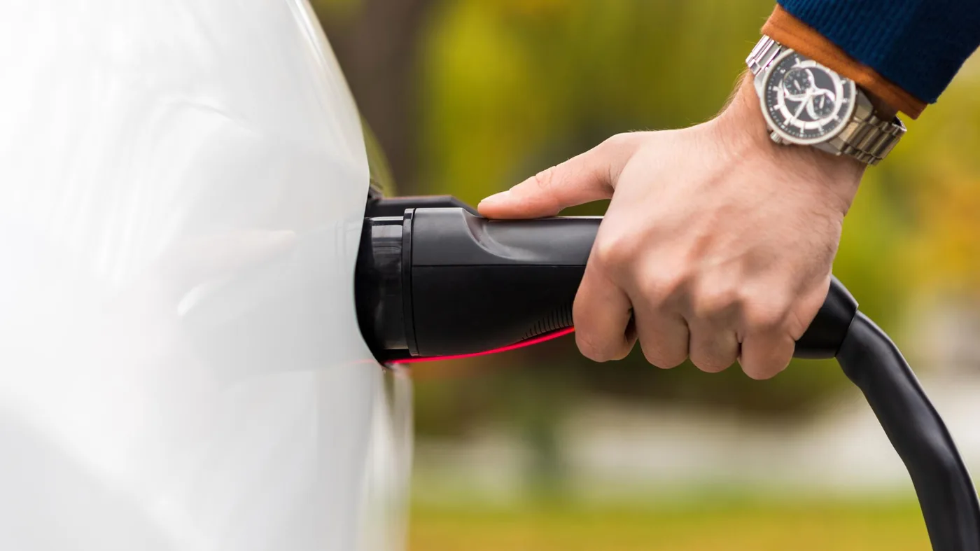 Elektrische auto die via een laadpaal is aangesloten op het energienet, symbool voor V2G-technologie