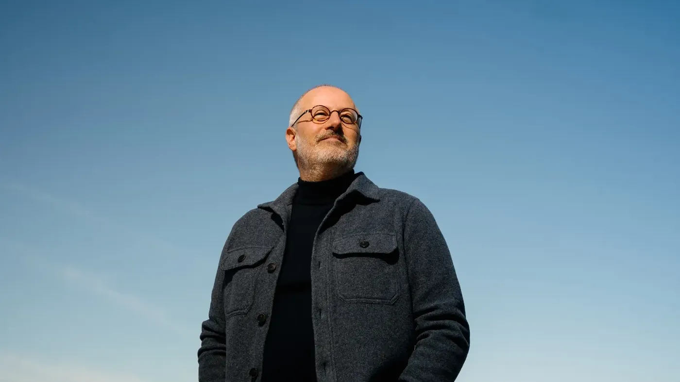 Peter Desmet kijkt omhoog tegen een blauwe lucht